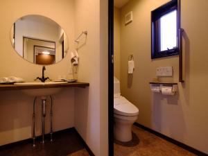 a bathroom with a toilet and a sink and a mirror at The Sense of Wonder Holistic Glamping in Yufuin