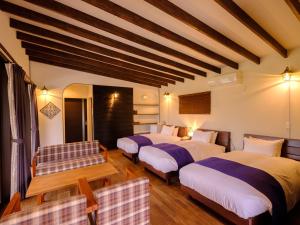 ein Hotelzimmer mit 3 Betten und einem Tisch in der Unterkunft The Sense of Wonder Holistic Glamping in Yufu
