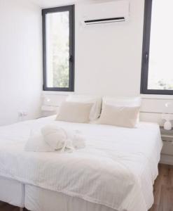 a white bedroom with a white bed with a bow on it at Golden Beach / De Shalit in Herzliyya B