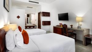 a hotel room with two beds and a desk at Lynnaya Urban River Resort in Siem Reap