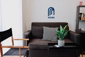 a living room with a brown couch with a plant on a table at Homi Oasis 和逸绿洲 in Kota Kinabalu