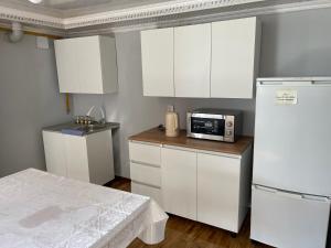 a kitchen with white cabinets and a microwave on a counter at Paradise Turkistan in Türkistan