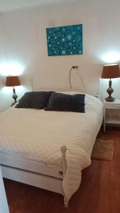 1 dormitorio con 1 cama blanca grande y 2 lámparas en Cabaña y Hospedaje Rural La Familia, en Dalcahue