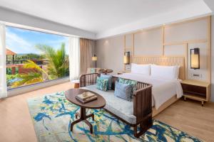 a bedroom with a bed and a couch and a table at The Westin Goa in Vagator