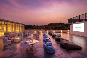 a rooftop patio with couches and tables and a screen at The Westin Goa, Anjuna in Anjuna