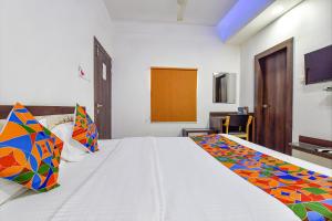 a bedroom with a white bed with colorful pillows at Hotel Vandana Palace in Kota