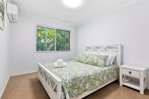ein weißes Schlafzimmer mit einem Bett und einem Fenster in der Unterkunft Casa Del Mare - 3 Bedroom Home in Burrum Heads