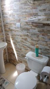 a bathroom with a white toilet and a stone wall at Cabaña y Hospedaje Rural La Familia in Dalcahue