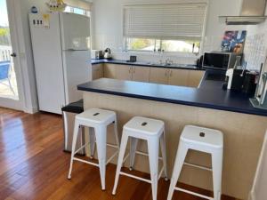 a kitchen with two stools and a counter with a refrigerator at Sinclair Surfside Stay in Surf Beach