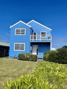 a blue house with a balcony on a lawn at Sinclair Surfside Stay in Surf Beach