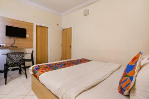 a bedroom with a bed and a chair and a television at FabHotel Heritage Palace in Aurangabad