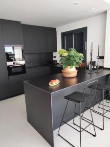 a kitchen with a black island with chairs and a plant at Faro 3 in Torredembarra