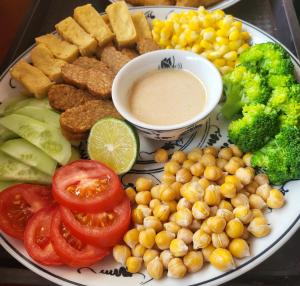 a plate of food with tomatoes broccoli chickpeas and a dip at Tam Coc Ngo Đong Homestay in Ninh Binh
