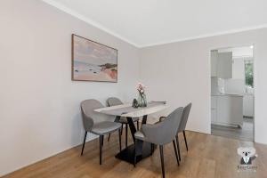 a white dining room with a table and chairs at KozyGuru / Clovelly / 2B Kozy APT / NCL037 in Sydney