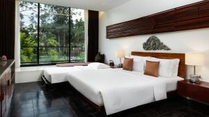 two beds in a hotel room with a large window at Lynnaya Urban River Resort in Siem Reap