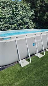 a swimming pool sitting on the grass next to a bush at Maison paisible et ensoleillée in Avignon