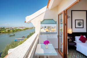 uma varanda com uma cama e vista para um rio em Lantana Riverside Hoi An Boutique Hotel & Spa em Hoi An