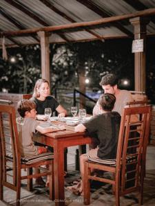 a family sitting at a wooden table with wine glasses at Birds Paradise Inn in Udawalawe