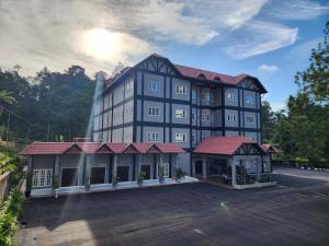 un grand bâtiment noir avec toit rouge dans l'établissement Fathers Guesthouse, à Tanah Rata