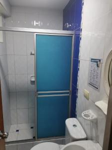 a bathroom with a toilet and a blue shower door at Hostal Puerto Ingles in Ilo