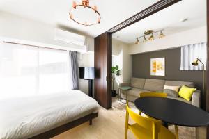 a bedroom with a bed and a table and yellow chairs at MAT Oshiage in Tokyo