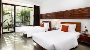 two beds in a hotel room with white and orange pillows at Lynnaya Urban River Resort in Siem Reap