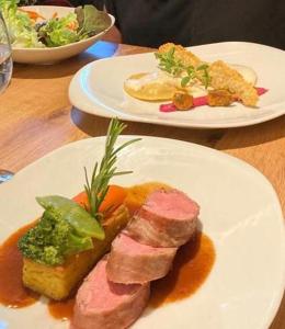 dwie talerze jedzenia na drewnianym stole w obiekcie Haus Vilgrassa w mieście St. Gallenkirch