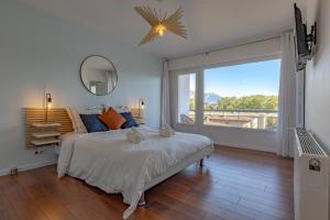 Dormitorio blanco con cama y ventana grande en L'échappee du 36 - 4 chambres dans le Triangle d'Or à 100m du lac, parking gratuit, en Annecy