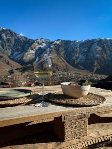 a glass of wine sitting on a table with a bowl of food at Cottage Toladi in Kazbegi