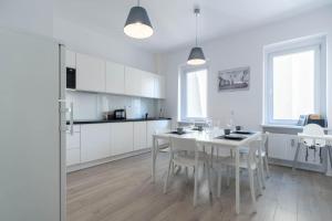 cocina blanca con mesa blanca y sillas en Blue Apartment Browar Central, en Poznan