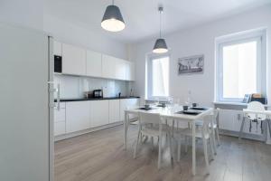 a white kitchen with a white table and chairs at Blue Apartment Browar Central in Poznań