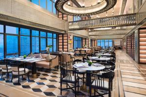 a restaurant with tables and chairs in a room with windows at Yiwu Kaison K Hotel in Yiwu