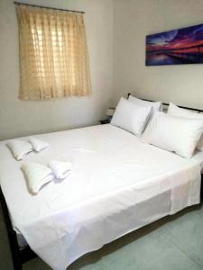 a large white bed with two pillows on it at Captain John's Apartment in Diafani