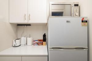 a white kitchen with a refrigerator and a microwave at Great Location! Close to Restaurants & Train! in Brisbane