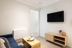 a living room with a blue couch and a tv at Great Location! Close to Restaurants & Train! in Brisbane