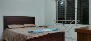 Schlafzimmer mit einem Bett und einem großen Fenster in der Unterkunft Luxurious Apartment with a pool and gym near Trivandrum railway station in Thiruvananthapuram