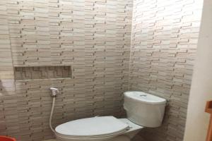 La salle de bains est pourvue de toilettes blanches et d'un mur en briques. dans l'établissement OYO 92818 Penginapan Garuda Syariah, 