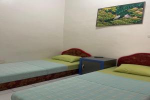 - une chambre avec 2 lits, une table et un tableau dans l'établissement OYO 92818 Penginapan Garuda Syariah, 
