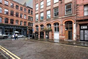 a city street with buildings and people with an umbrella at GuestReady - Northern Quarter Urban Escape in Manchester