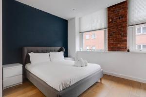 een slaapkamer met een bed met een blauwe muur bij GuestReady - Northern Quarter Urban Escape in Manchester