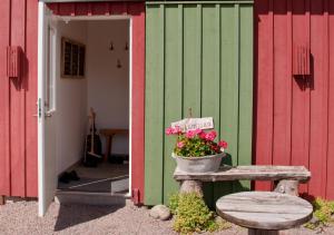 a green and red building with a bench and a pot of flowers at Escape to PaulssonPaleo in Simlångsdalen
