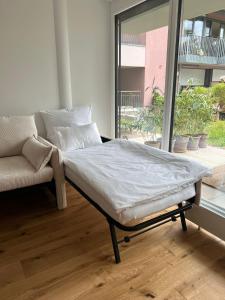 1 cama y 1 sofá en una habitación con ventana en Urban Lodges - Studio Apartments am Seerhein en Konstanz