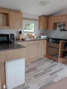 uma cozinha com armários de madeira e um forno com placa de fogão em Lapwing Lodge em Louth