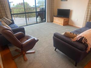 a living room with two couches and a television at Aqua Views - Kuratau Holiday Home in Kuratau