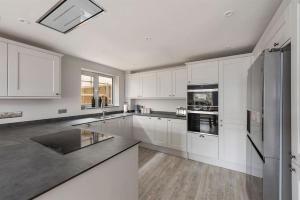 a kitchen with white cabinets and a black counter top at The Beach Hut in Seasalter