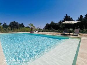a swimming pool with two chairs and an umbrella at Gîte Mas La Bohème Piscine Parking Privé L'Isle-Sur-La-Sorgue in L'Isle-sur-la-Sorgue