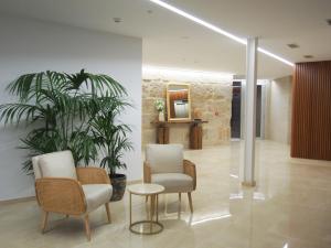 een lobby met 2 stoelen, een tafel en een spiegel bij HOTEL BOUTIQUE VILAVELLA in O Grove
