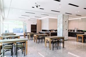 a dining room with tables and chairs and a kitchen at Hoping Mori Hotel in Heping