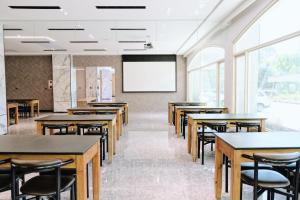 a classroom with tables and chairs and a projection screen at Hoping Mori Hotel in Heping
