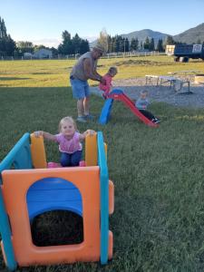 a man and two children playing in a playground at Glacier Acres Guest Ranch in Columbia Falls